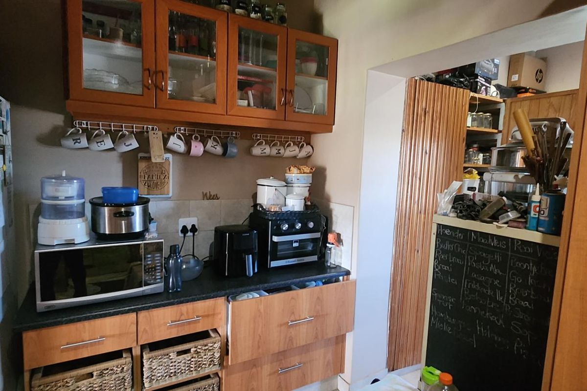 A functional kitchen area featuring wooden cabinetry, laminate countertops, and a tiled backsplash, providing practical storage and workspace.