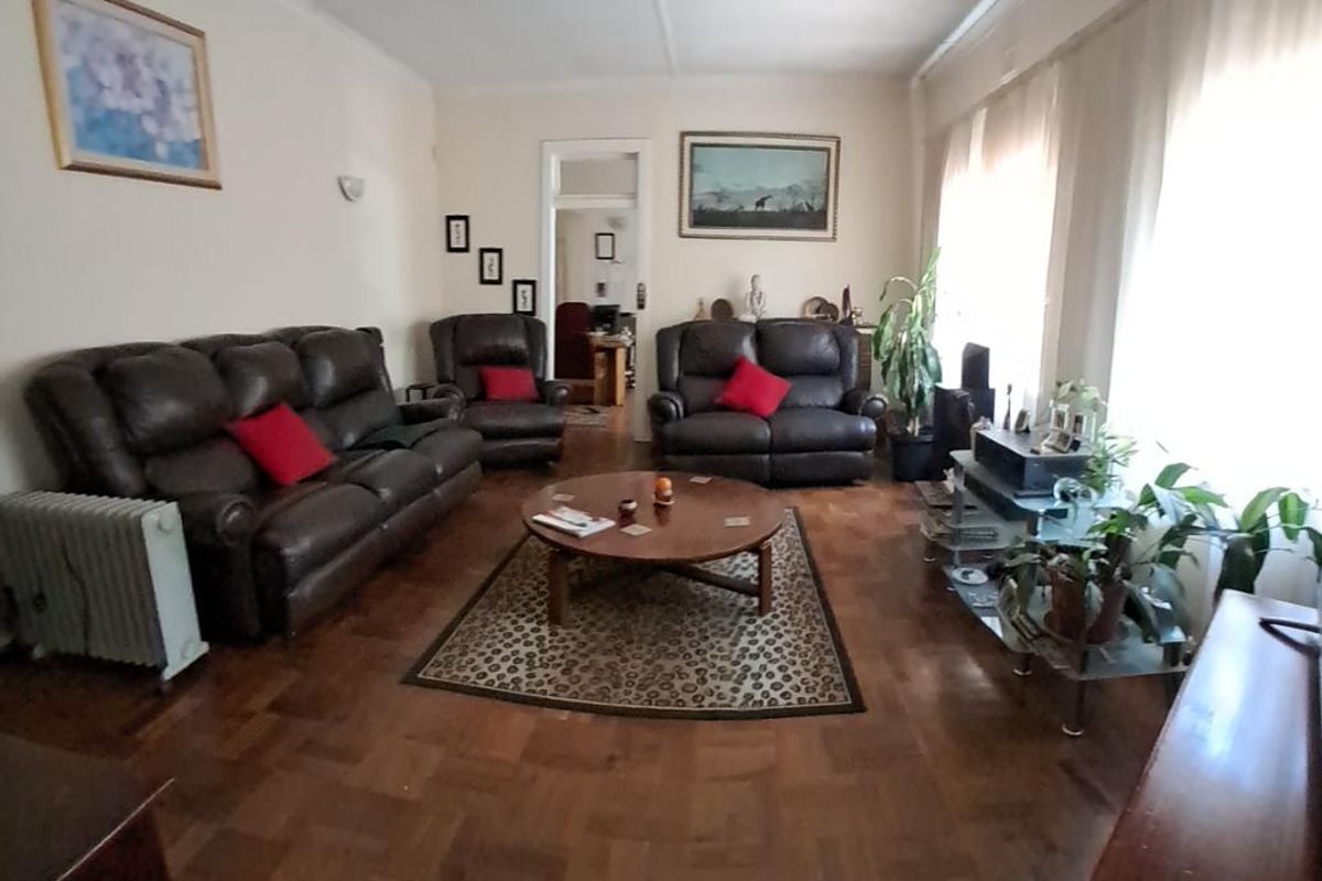 Spacious living room featuring traditional parquet flooring, large windows allowing natural light, and a classic layout suitable for comfortable family living.