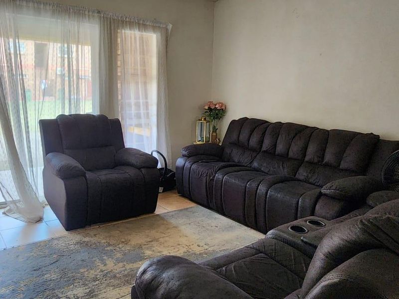 A comfortable living room featuring tiled flooring and a large sliding glass door that provides natural light and access to the exterior.
