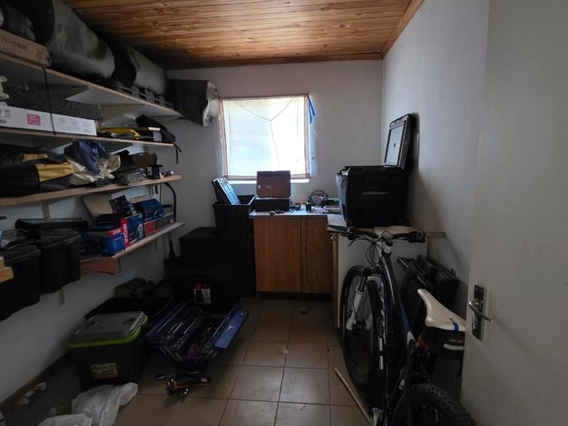 A functional utility or storage room featuring tiled flooring, timber ceiling, built-in shelving, and cabinetry, currently used for storage.