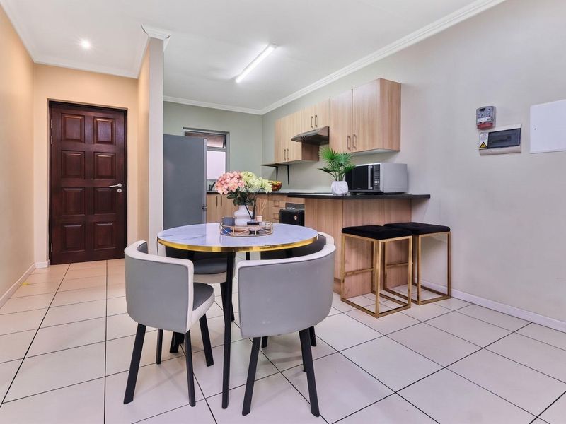 Open-plan kitchen and dining area featuring modern cabinetry, a breakfast counter, tiled flooring, and neutral wall finishes.
