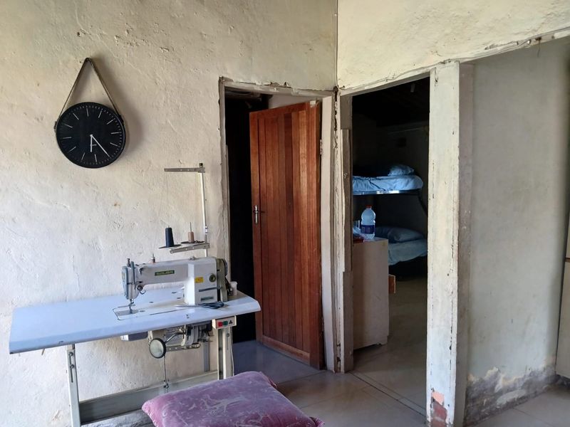 A hallway area showing signs of wear with visible plaster damage and peeling paint, leading into adjacent rooms with timber door frames.