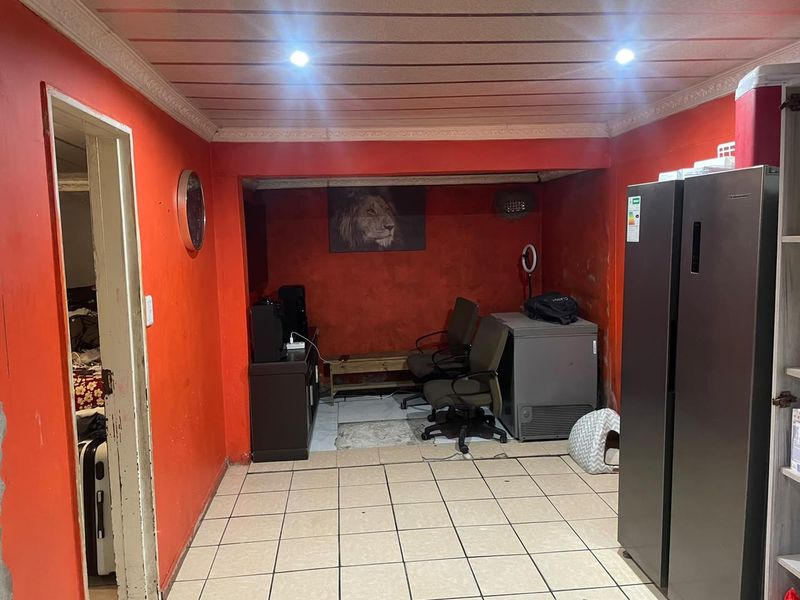 A living area featuring tiled flooring and recessed lighting, currently requiring cosmetic updates to the wall finishes and ceiling structure.