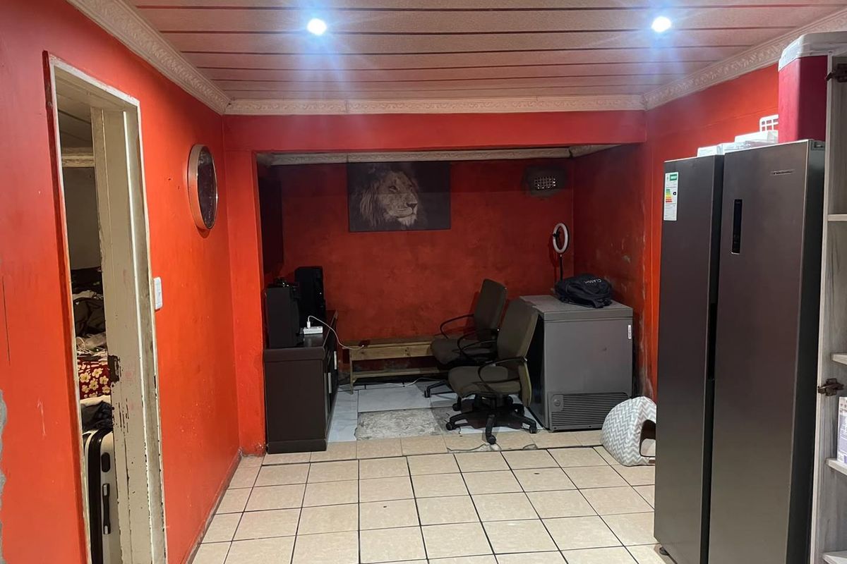 A living area featuring tiled flooring and recessed lighting, currently requiring cosmetic updates to the wall finishes and ceiling structure.