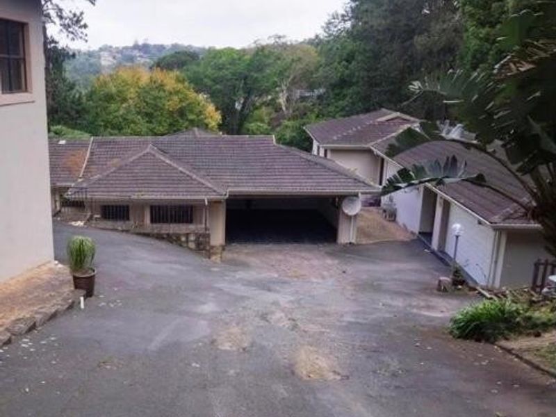 View of the property entrance featuring a large asphalt driveway leading to a double garage and residential building structure.