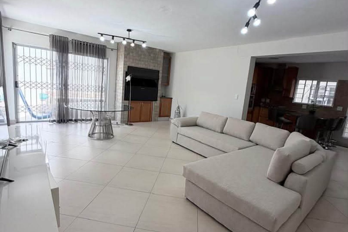 Spacious open-plan living area featuring large format floor tiles, a stone feature wall with built-in shelving, and direct access to the patio.