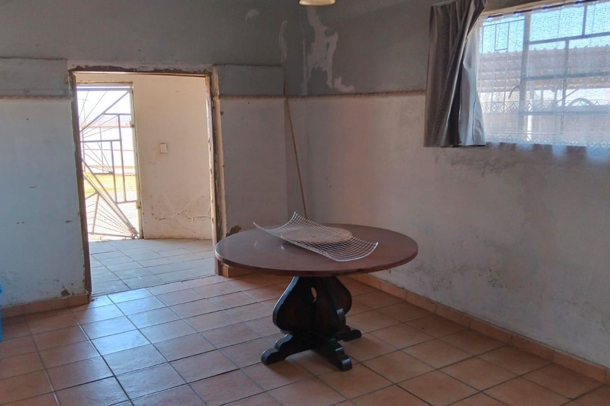 A living area featuring ceramic floor tiles and direct access to an outdoor space, requiring cosmetic wall repairs and updates to improve the interior condition.