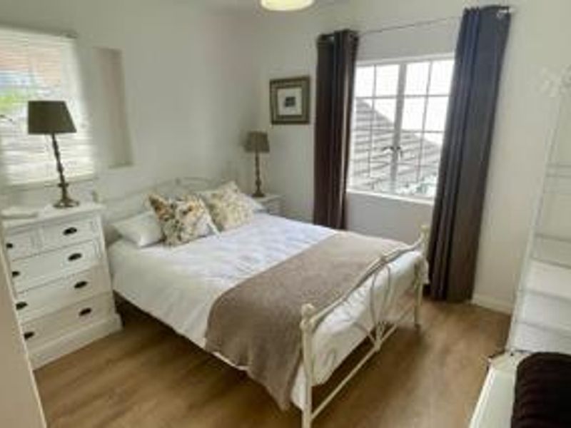 A bright and well-maintained bedroom featuring laminate flooring and dual aspect windows, providing a comfortable and inviting living space.