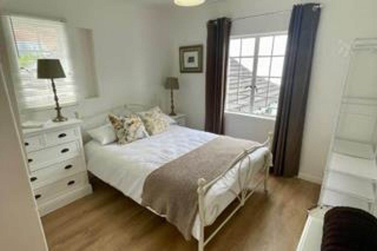 A bright and well-maintained bedroom featuring laminate flooring and dual aspect windows, providing a comfortable and inviting living space.