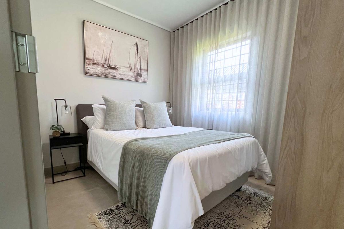 A well-maintained bedroom featuring neutral wall finishes, tiled flooring, and a window fitted with security bars and elegant floor-to-ceiling curtains.