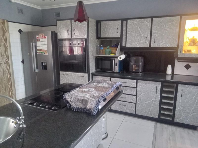 A functional kitchen featuring stone countertops, built-in oven, electric hob, and marble-effect cabinetry with ample storage space.