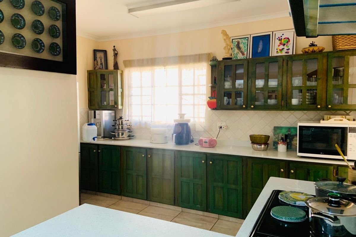 A functional kitchen featuring dark green cabinetry, light-colored countertops, tiled backsplash, and a built-in electric hob.