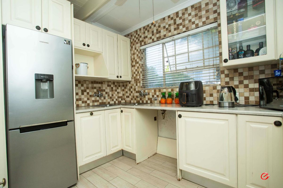 A functional kitchen featuring cream-colored cabinetry, a tiled backsplash, and a dedicated space for an under-counter appliance.