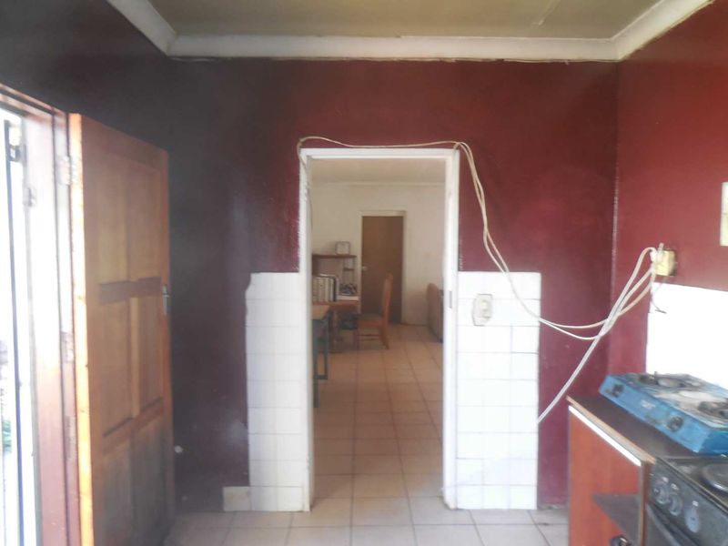 A kitchen area featuring tiled splashbacks and a built-in stove, requiring cosmetic updates and electrical maintenance to improve the overall finish.