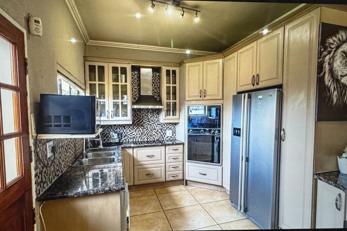 A functional kitchen featuring granite countertops, mosaic tile backsplash, built-in oven, extractor fan, and ample cabinetry with tiled flooring.