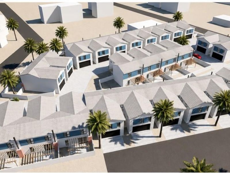 An aerial perspective of a modern townhouse development featuring multiple units with pitched roofs, private garages, and landscaped outdoor areas.
