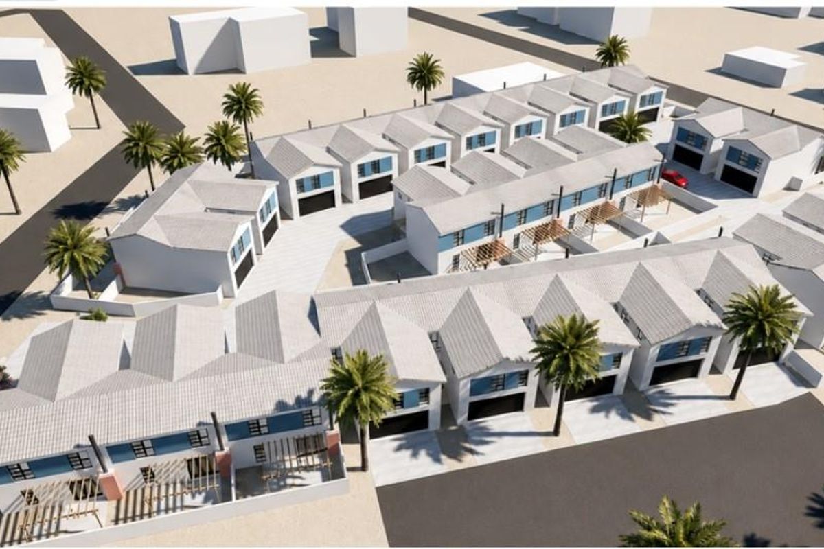 An aerial perspective of a modern townhouse development featuring multiple units with pitched roofs, private garages, and landscaped outdoor areas.