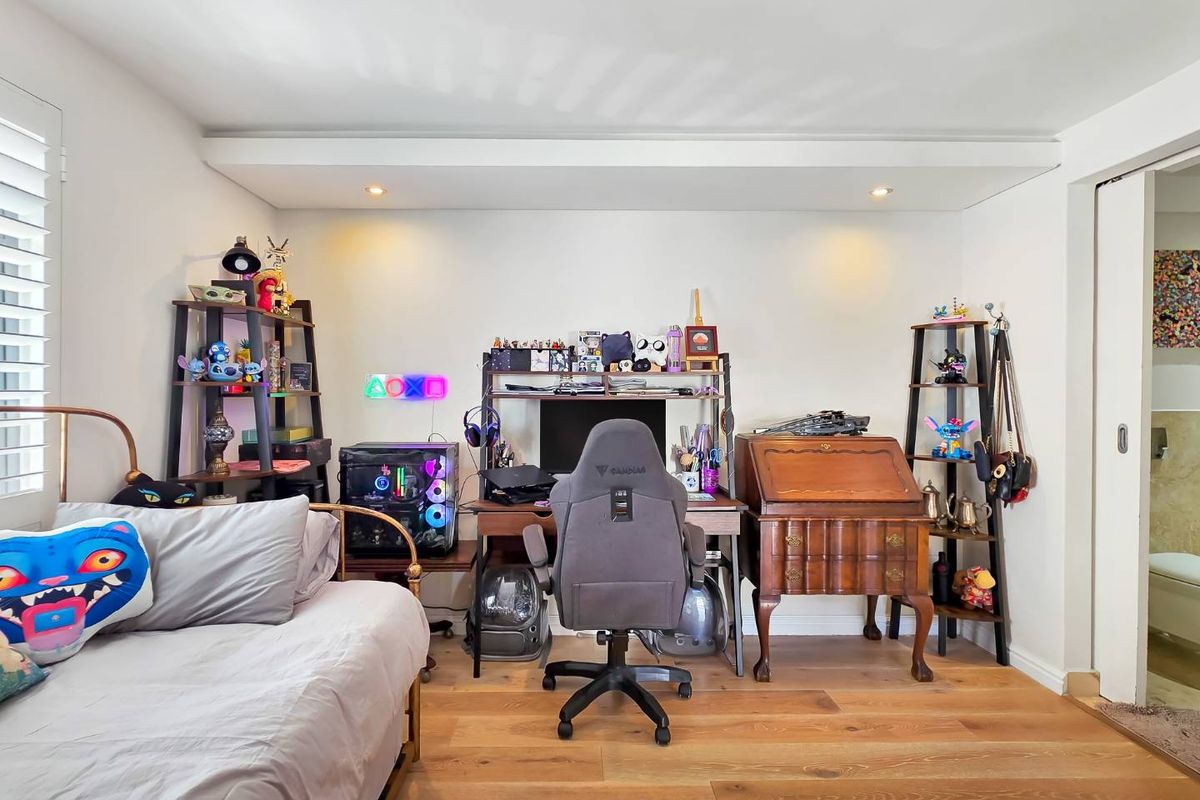 A well-maintained bedroom featuring hardwood flooring, recessed downlighting, and a sliding door leading to an adjacent space.