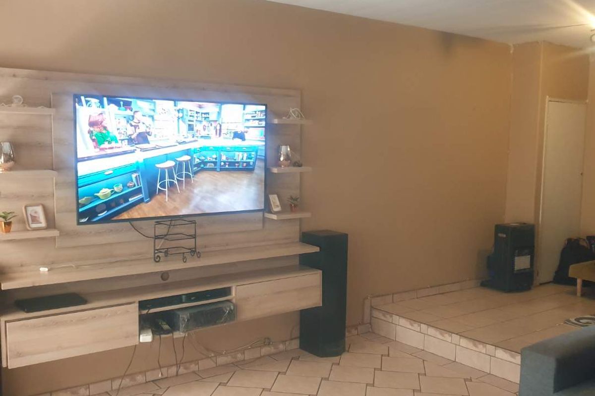 Living room featuring a built-in media unit, tiled flooring, and a raised platform area, offering a functional space for entertainment.