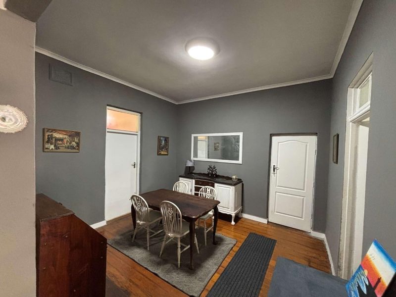 A dining room featuring dark grey walls, original hardwood flooring, and a coved ceiling with a central light fixture.
