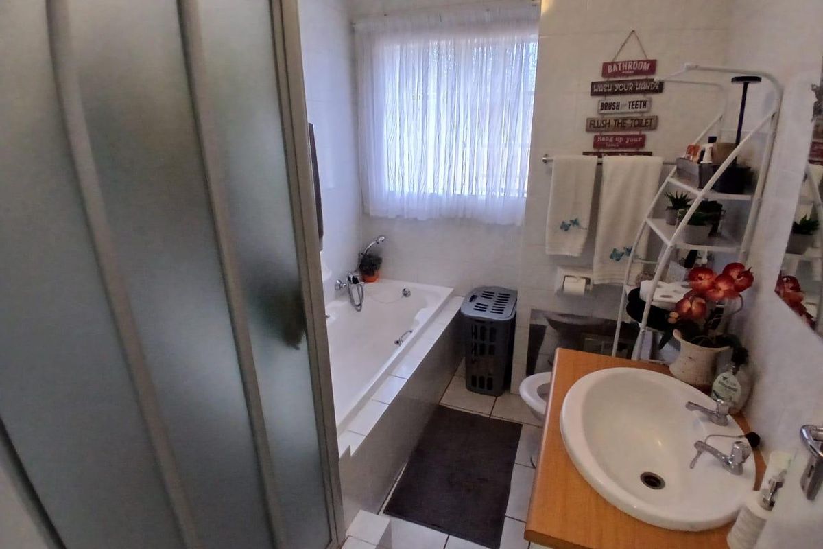 A functional bathroom featuring a built-in bathtub, a separate shower enclosure, and a vanity basin with tiled flooring and wall finishes.