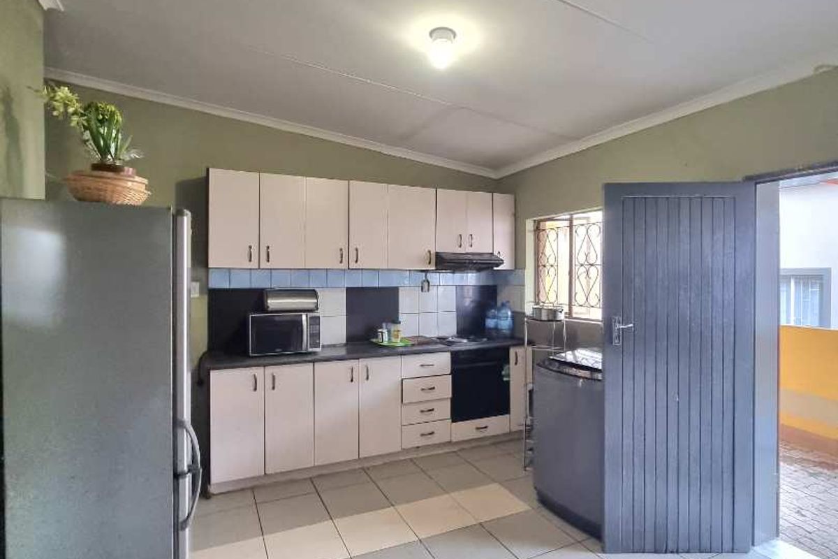 A functional kitchen featuring built-in cabinetry, a tiled floor, and direct access to an outdoor area.
