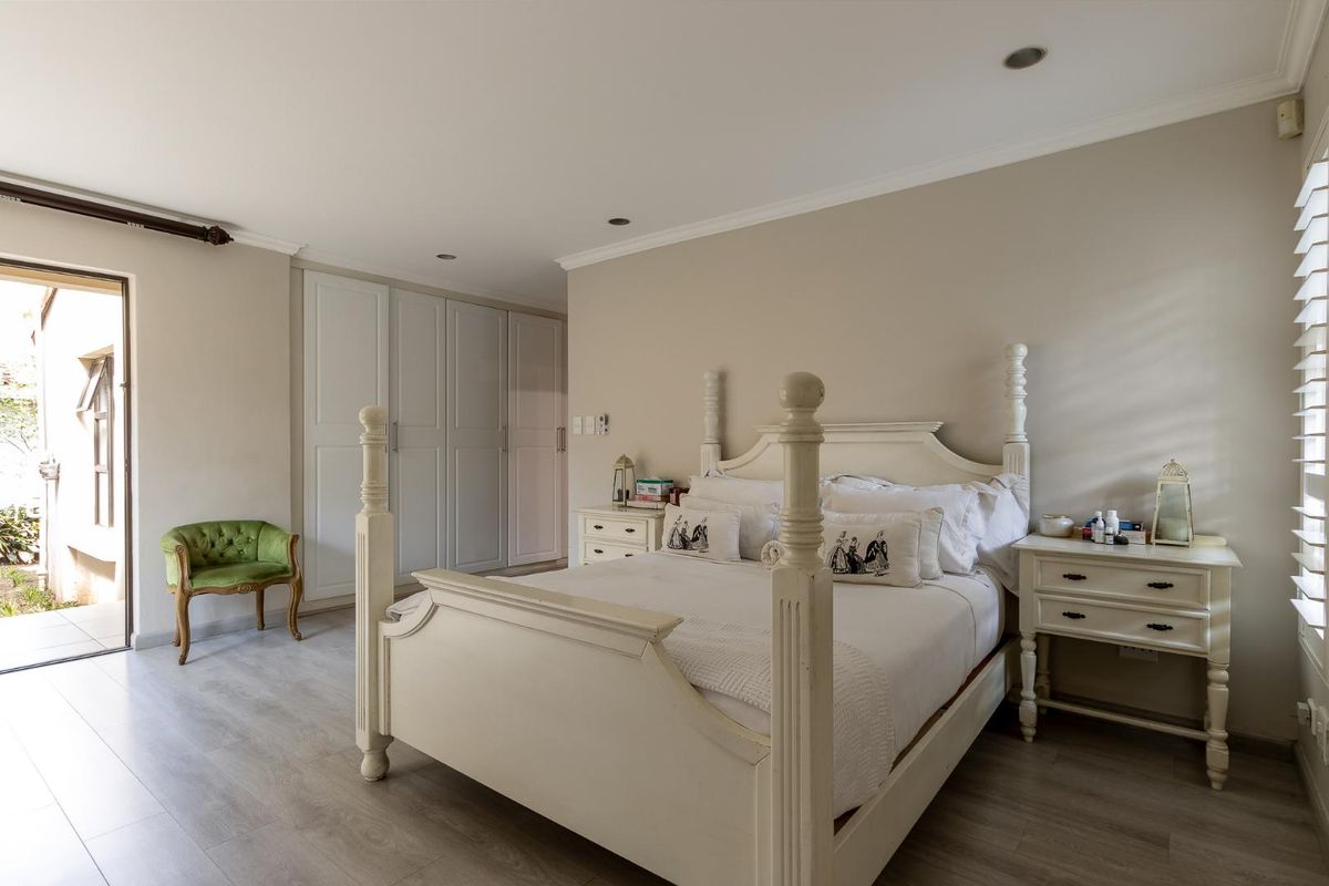 Spacious bedroom featuring built-in wardrobes, recessed ceiling lighting, and direct access to an outdoor patio area through a glass door.