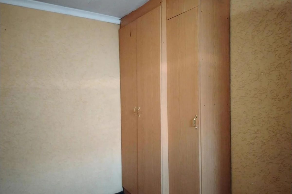 A bedroom featuring built-in wooden cupboards and textured wall finishes, offering a blank canvas for potential renovation and modernization.