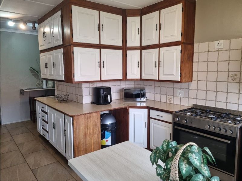 A functional kitchen featuring two-tone cabinetry, tiled backsplash, and a built-in gas stove with oven, offering a practical layout for daily cooking.