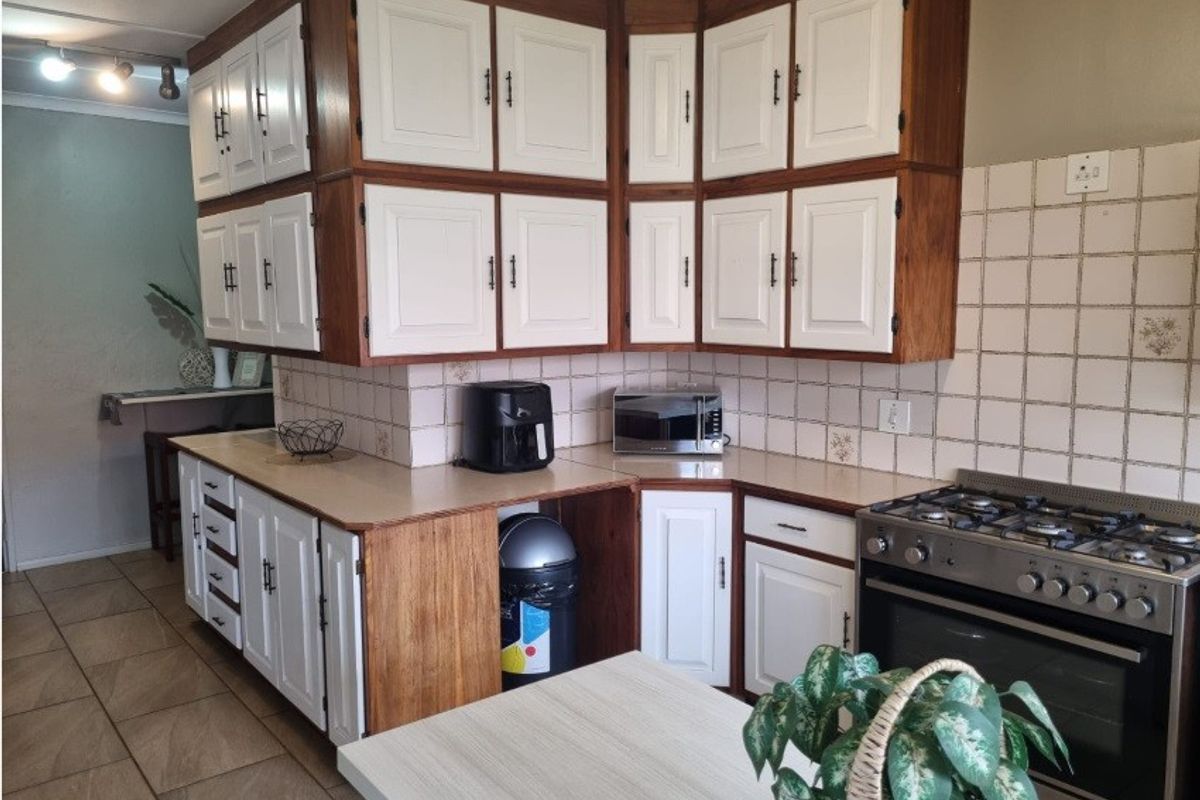 A functional kitchen featuring two-tone cabinetry, tiled backsplash, and a built-in gas stove with oven, offering a practical layout for daily cooking.