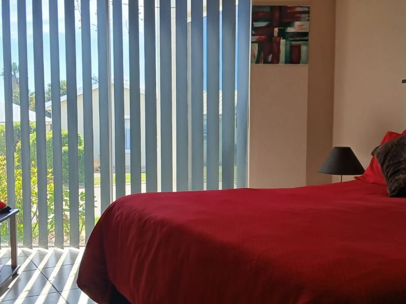A bedroom featuring tiled flooring and vertical blinds providing natural light and access to the exterior.