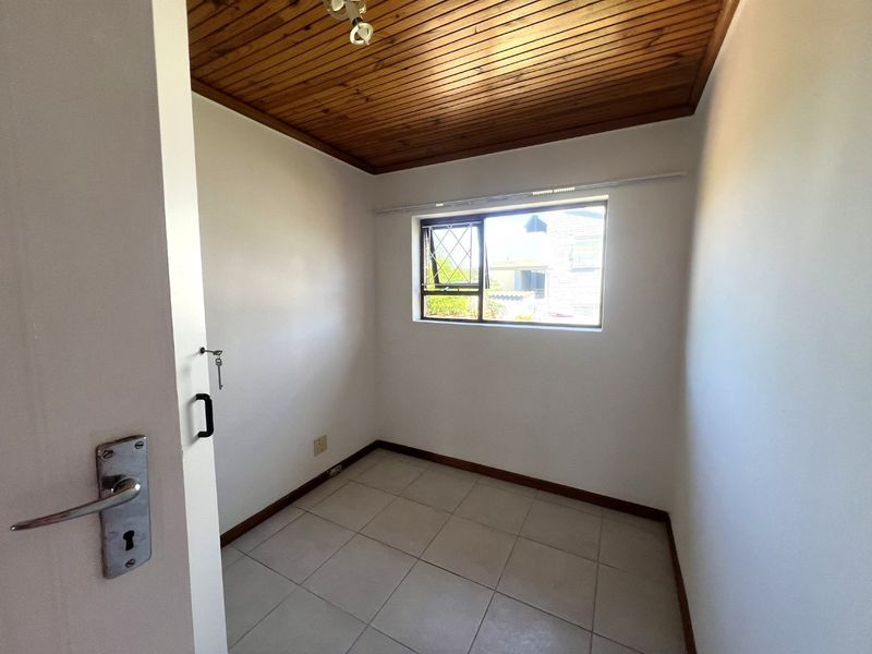 A compact, empty bedroom featuring tiled flooring and a timber-paneled ceiling, offering a neutral space ready for personalization.