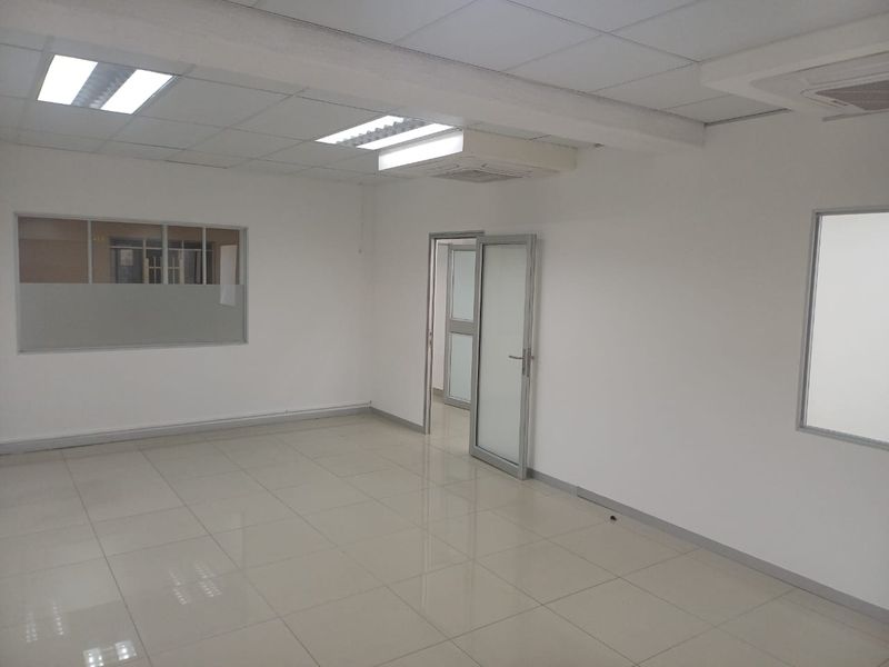 A clean, empty office space featuring tiled flooring, suspended ceilings with recessed lighting, and internal glass partitions for a professional, bright work environment.