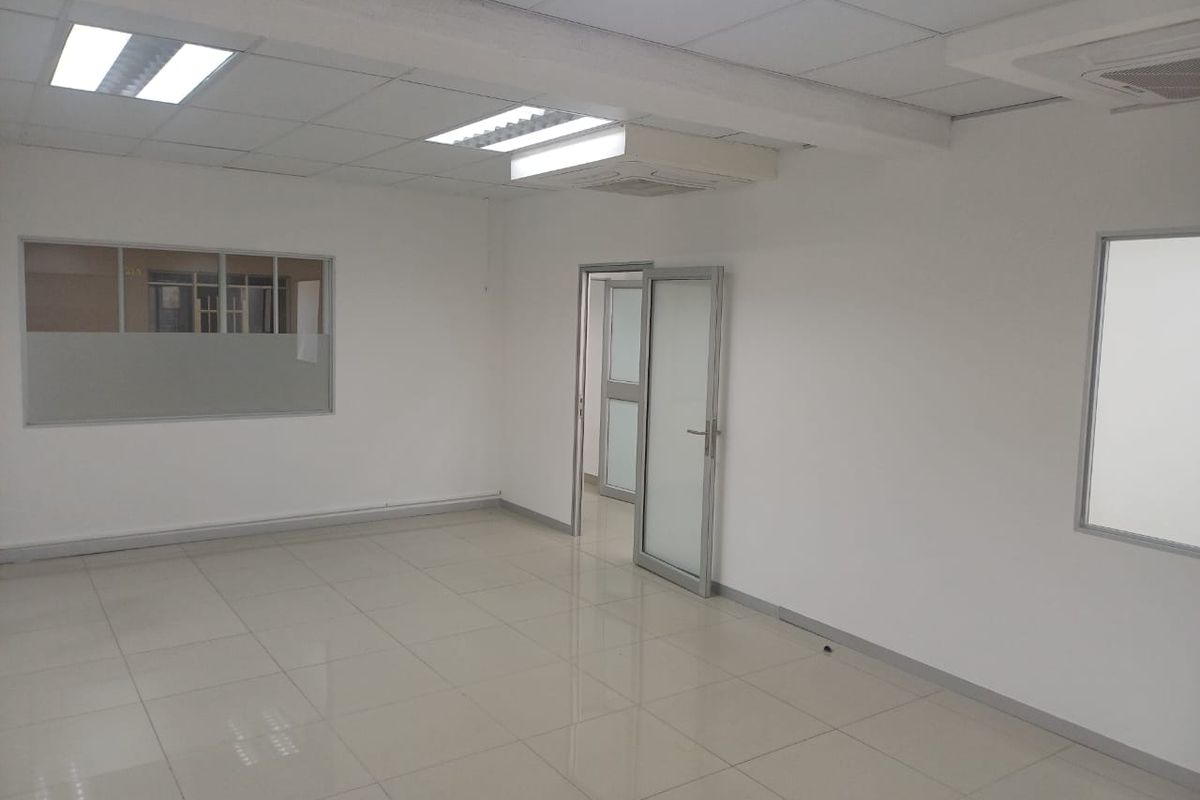 A clean, empty office space featuring tiled flooring, suspended ceilings with recessed lighting, and internal glass partitions for a professional, bright work environment.