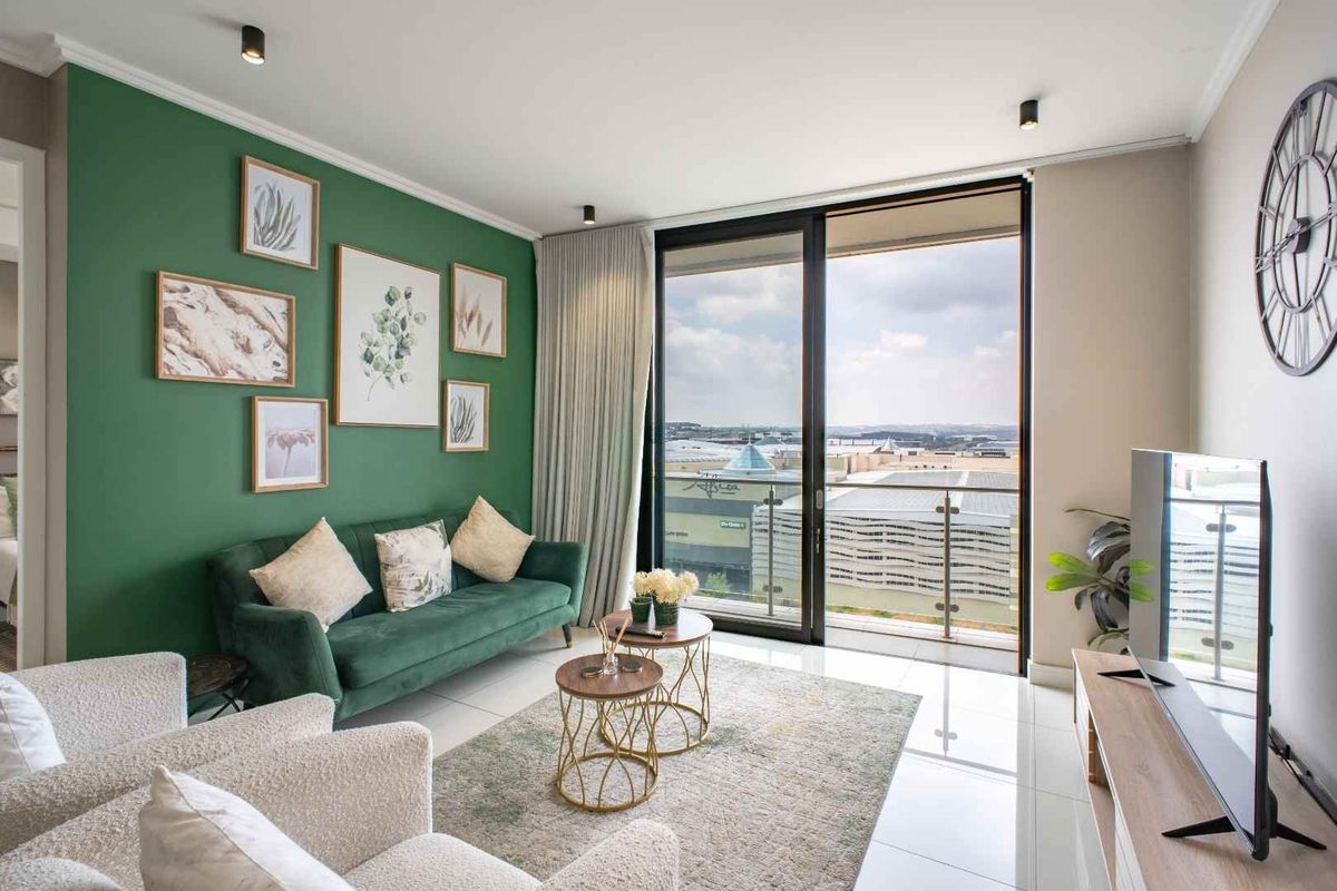 Modern living room featuring large sliding glass doors leading to a balcony with expansive city views and sleek tiled flooring.