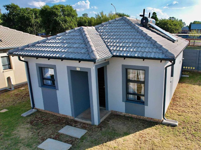 A well-maintained single-story residential home featuring a tiled roof, solar water heating system, and a clean, modern exterior facade.