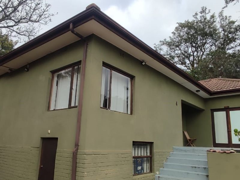 Front elevation of a residential apartment building featuring painted brick walls, tiled roof, and concrete entrance steps.