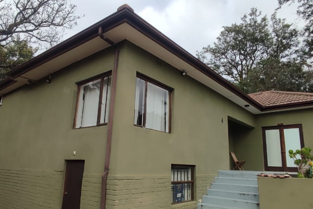 Front elevation of a residential apartment building featuring painted brick walls, tiled roof, and concrete entrance steps.