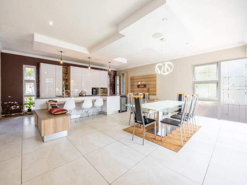 Spacious open-plan kitchen and dining area featuring modern cabinetry, a breakfast bar, tiled flooring, and recessed lighting, offering a versatile living space.