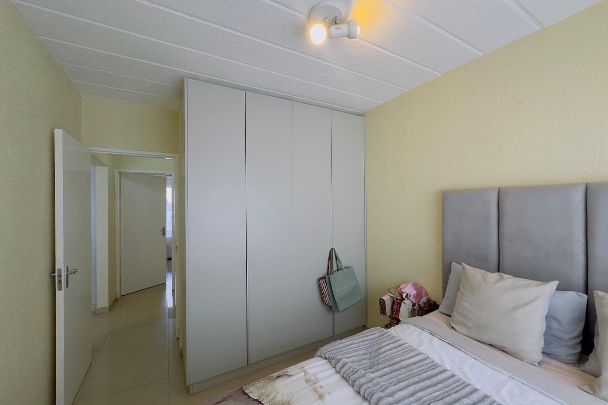 A bedroom featuring built-in floor-to-ceiling wardrobes, tiled flooring, and a textured ceiling finish, providing functional storage and a neutral living space.