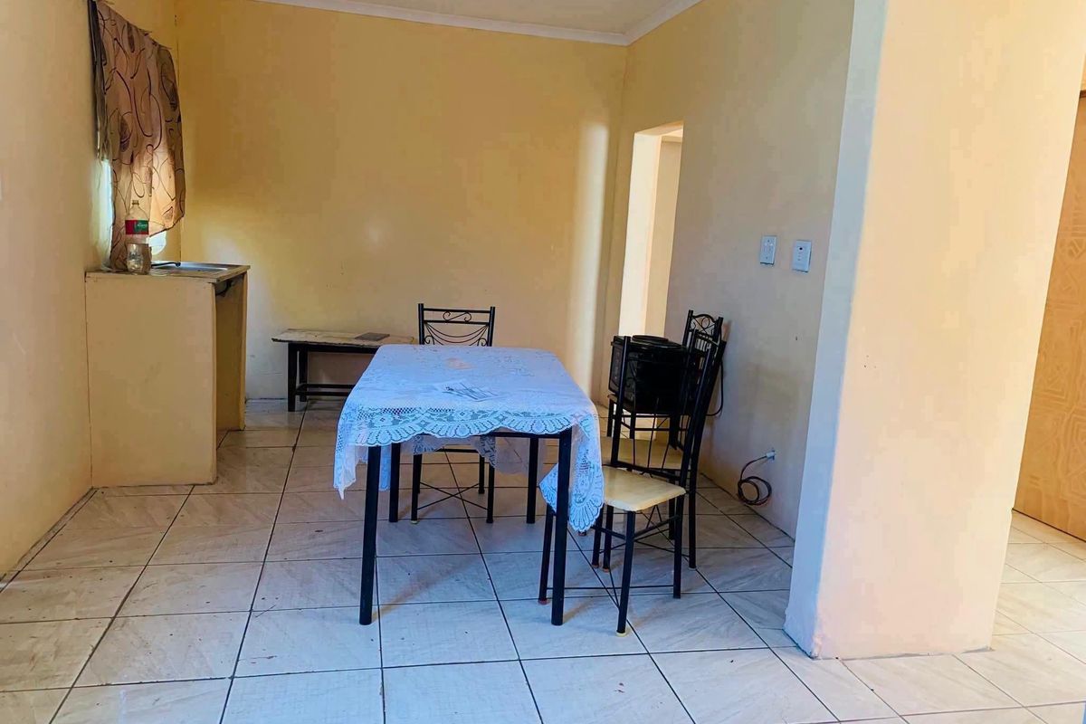 Open plan living and dining area featuring tiled flooring and a basic built-in sink unit, offering a functional space with potential for modernization.