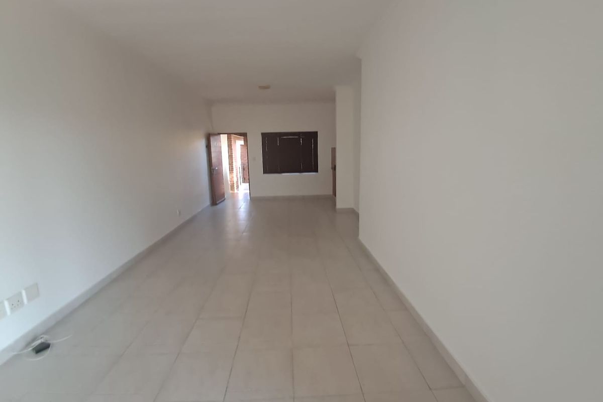 A spacious, empty living area featuring neutral tiled flooring and white walls, providing a blank canvas for interior design and furniture placement.