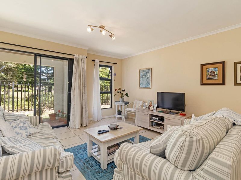A comfortable living room featuring tiled flooring, a large sliding glass door leading to the patio, and natural light from a top-hung window.