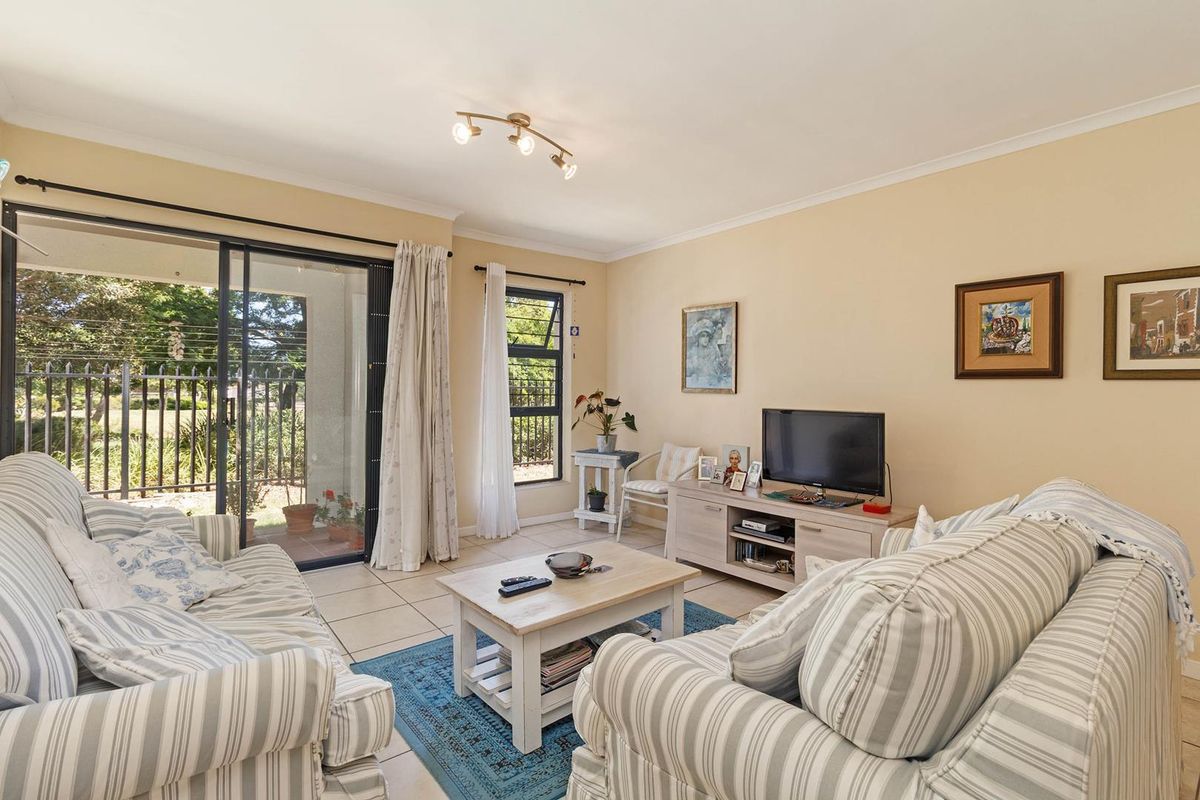 A comfortable living room featuring tiled flooring, a large sliding glass door leading to the patio, and natural light from a top-hung window.