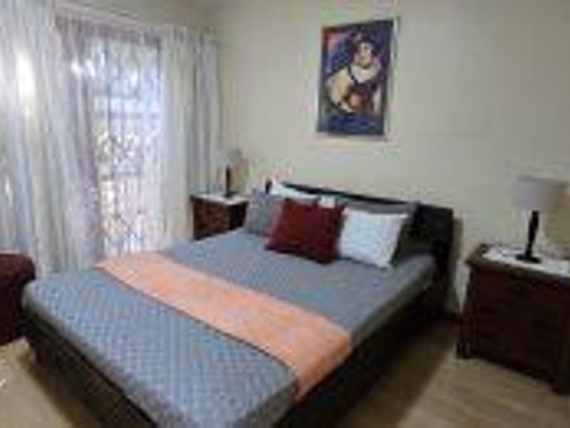 A functional bedroom featuring laminate flooring and a sliding door with a security gate, providing access to the exterior.