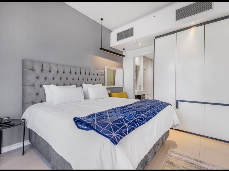 Modern bedroom featuring built-in cupboards, ducted air conditioning, and tiled flooring, with direct access to an en-suite bathroom.