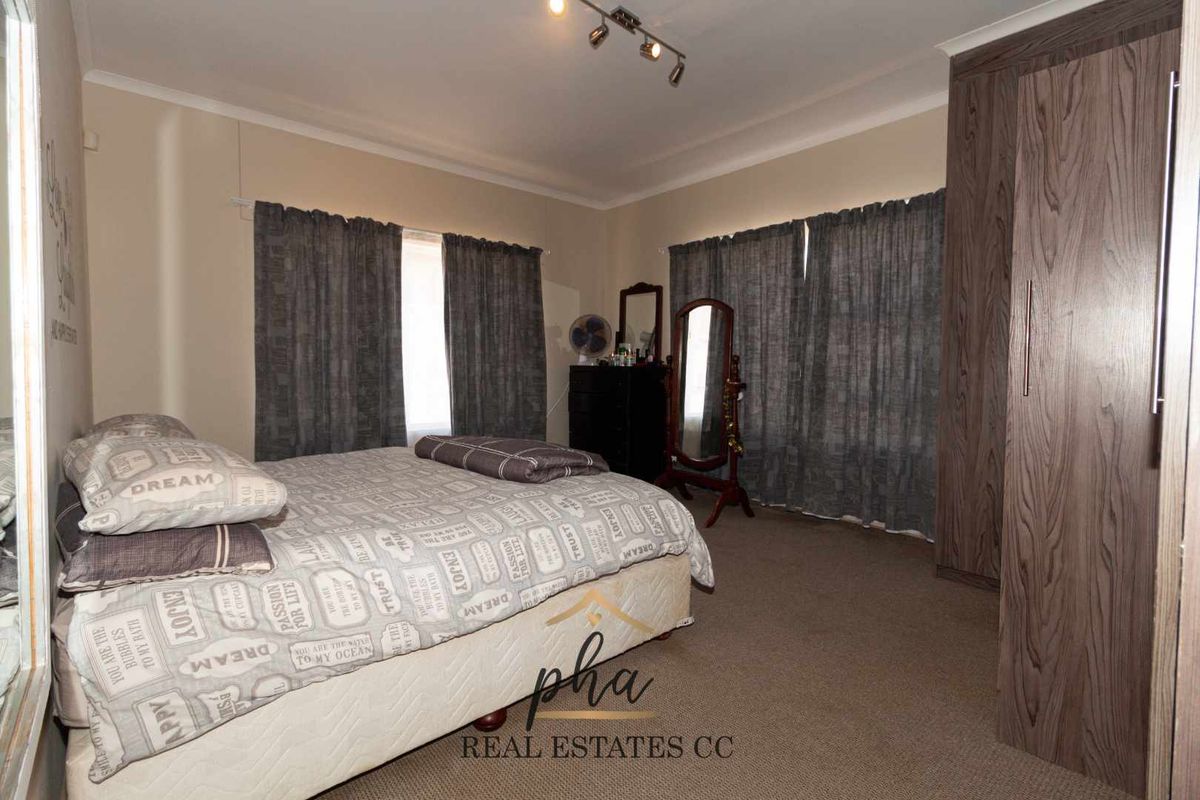A bedroom featuring built-in wooden cabinetry, carpeted flooring, and window treatments.