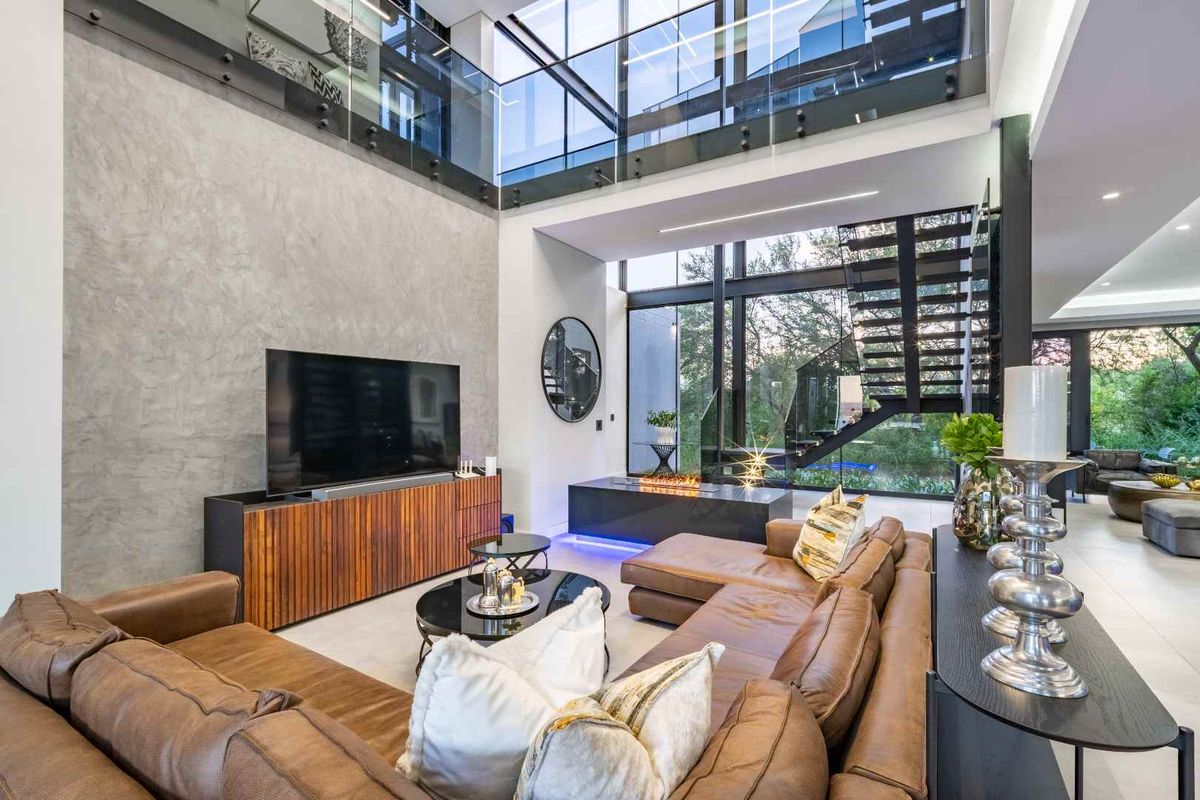Spacious double-volume living area featuring modern architectural design, large glass windows, a sleek fireplace, and high-end finishes throughout.