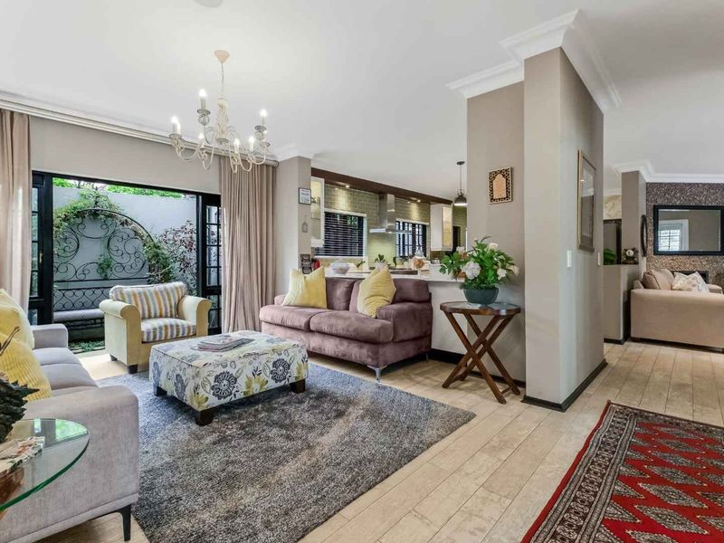 Spacious open-plan living area featuring tiled floors, crown molding, and seamless flow to an outdoor patio through large sliding glass doors.