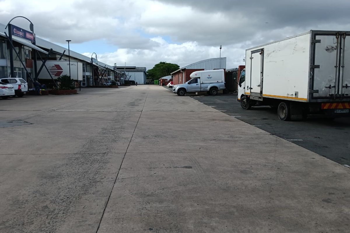 Wide concrete industrial yard providing access to multiple warehouse units with ample space for vehicle maneuvering and loading.
